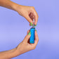 A girl with green nails screws a 510 cartridge into a blue Ooze Novex