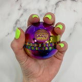 Holding a rainbow saturn grinder with neon green nails