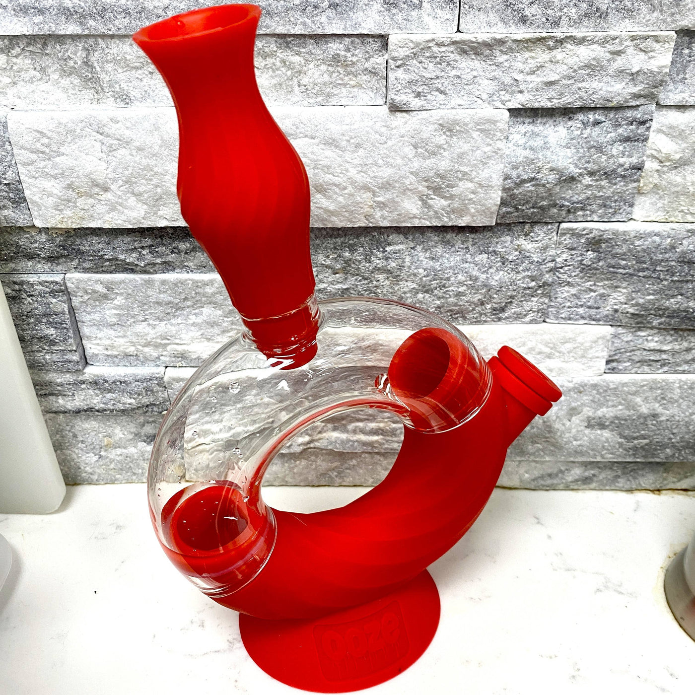 The scarlet Ooze Ozone silicone water pipe is shown on a counter with a gray tile background