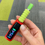 A close up of a hand holding The red Ooze Runt Mini Battery with the screen on, and cartridge with green tip and foam cover attached