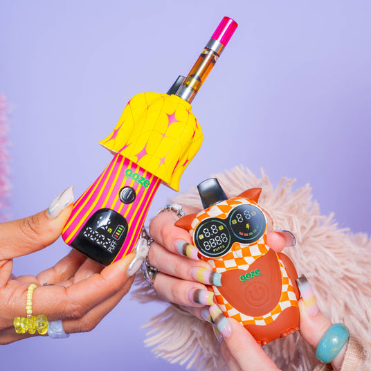 Hands holding a Shroom and hoot vape battery in front of a purple background