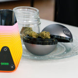 A silver saturn grinder has a few nugs in it waiting to be ground for the dry herb vape