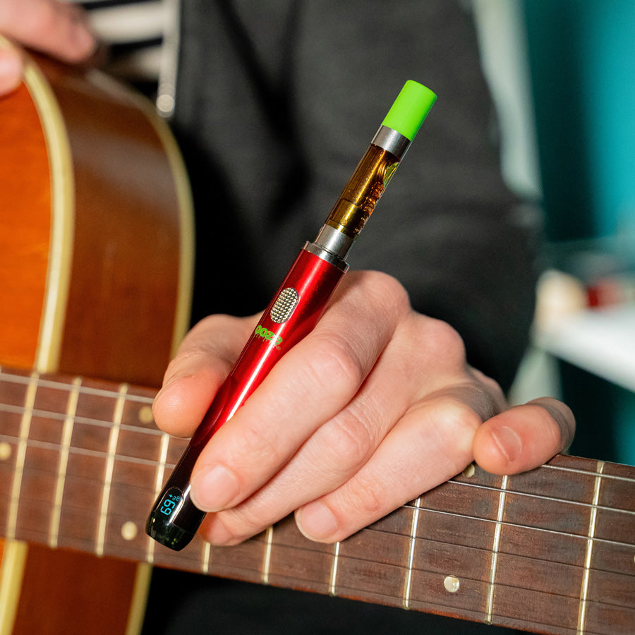 person holding red and black smart vape battery with guitar