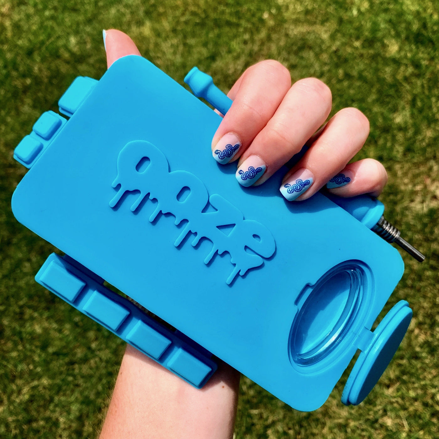 Hand holding a teal Ooze Slugger silicone dab dugout with all the slots open