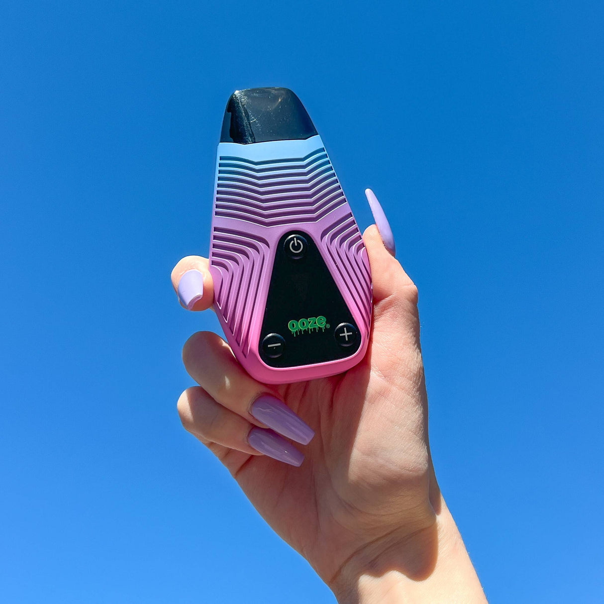 Person holding up Brink blue and purple weed vape with blue sky background