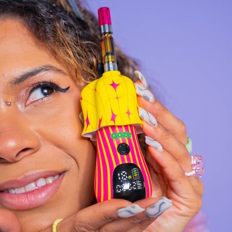 Person holding a twinkle Shroom vape device with a purple background