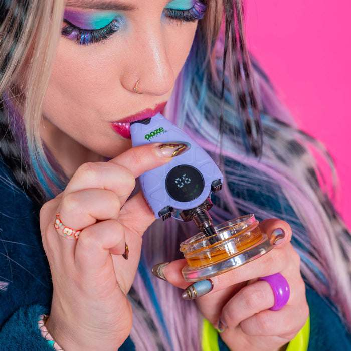Person using a purple Hover dab straw with a pink background