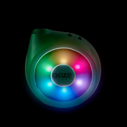 The Ooze Movez Speaker Vape in Mary Jade is shown in the dark with the rainbow LED lights illuminated.