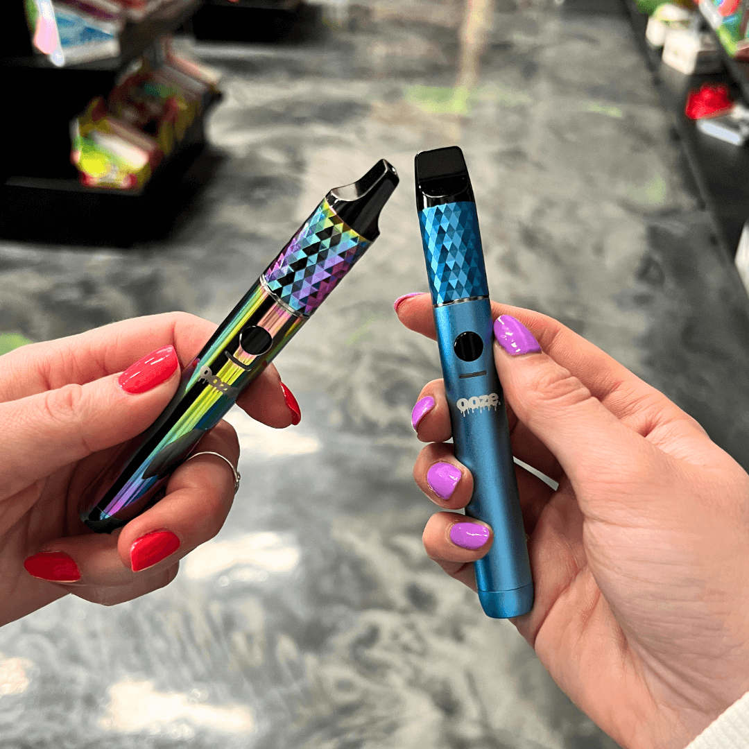 two people holding a blue Beacon dab pen and rainbow beacon dab pen