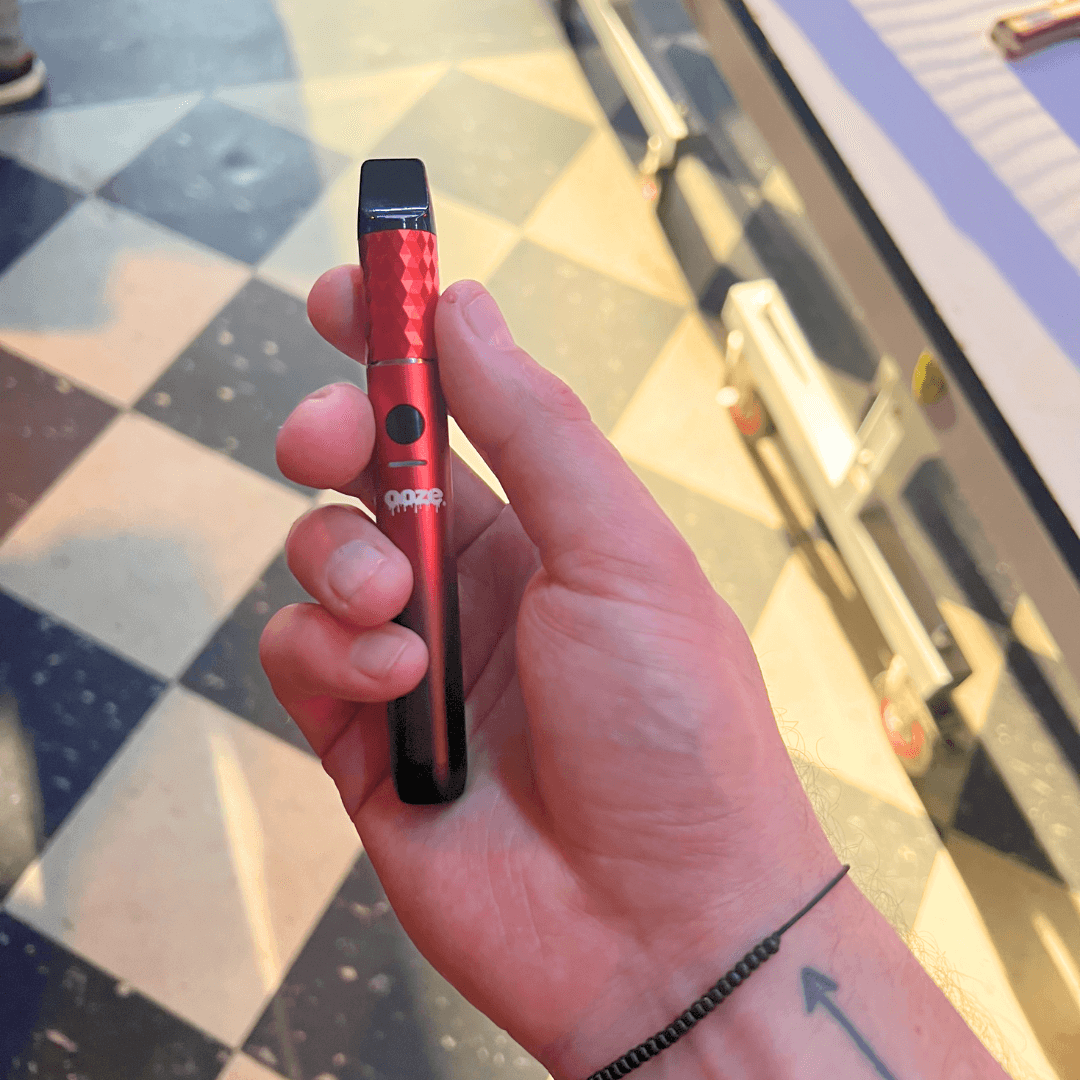 person holding red and black Beacon dab pen
