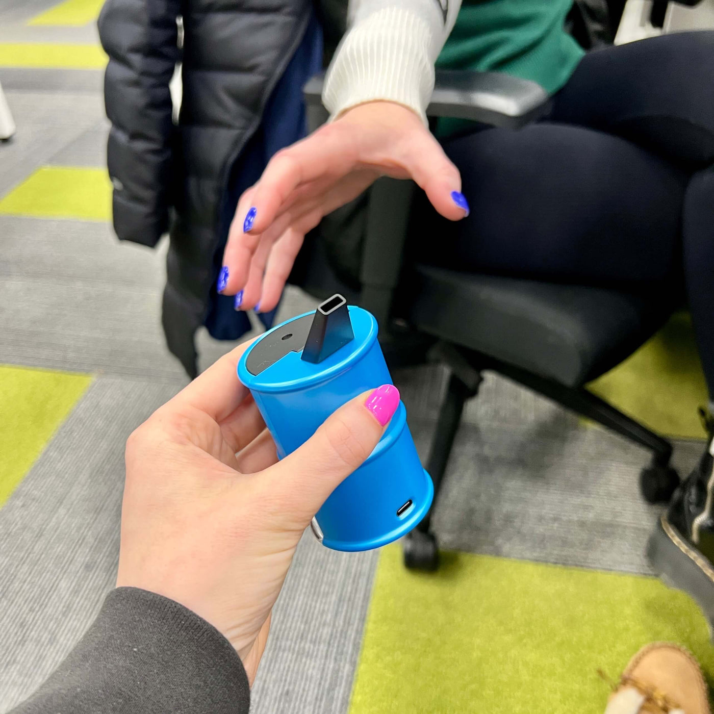 person passing blue Electro Barrel electric dab rig to another person