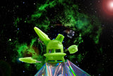 The green glow Ooze UFO is shown as a dab rig against a galaxy background with the dab straw and stash jar floating next to it